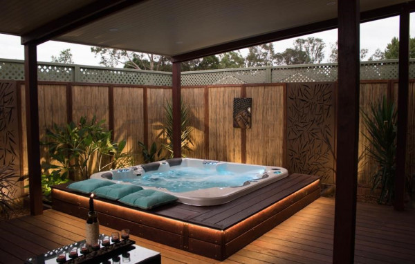 An intimate corner spa pool installation with bench seating surrounds and low garden lights.