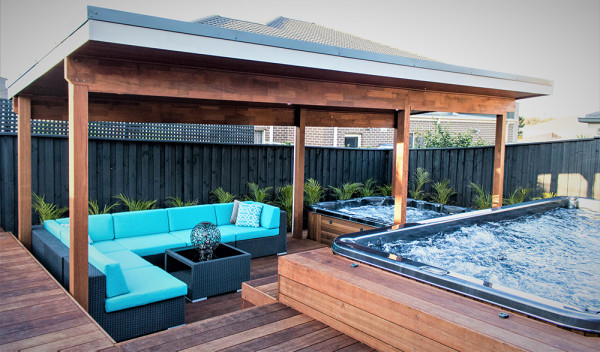 A swim spa, regular spa, and sheltered seating area come together to create a space for family time and entertaining